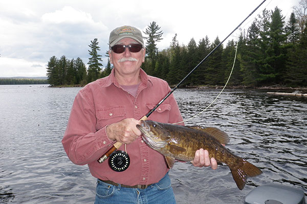 Man holding a fish he caught in Maine on an active family reunion - Northern Outdoors