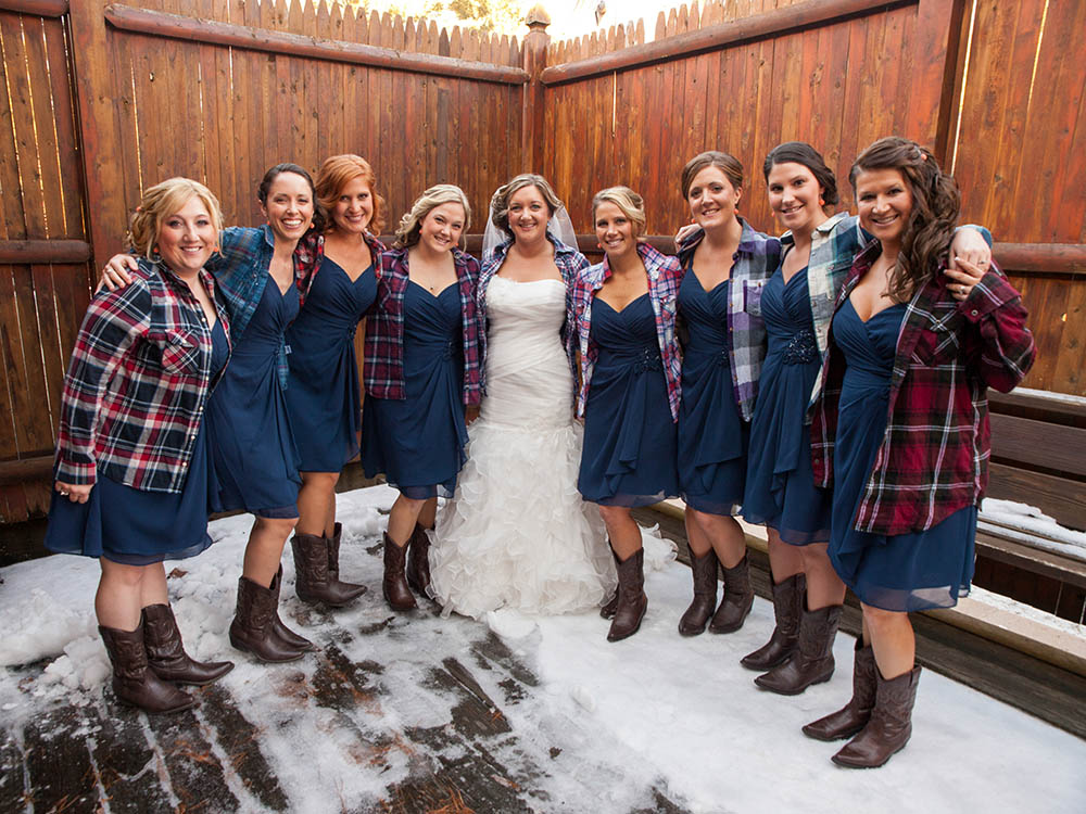 Bridal party in blue dresses and flannel shirts with cowboy boots - unique Maine winter wedding destination in The Forks