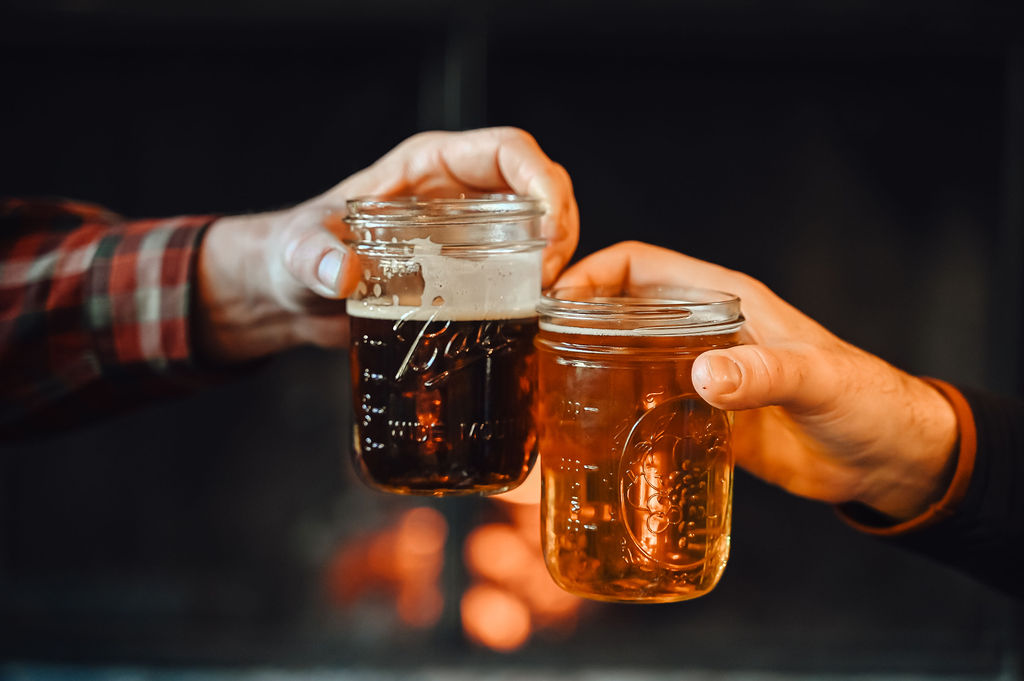 Pints cheering in front of fire at Kennebec river brewery.